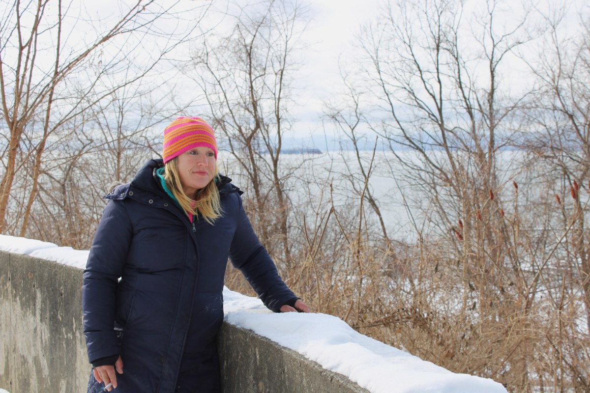 A woman leaning against a concrete wall.
