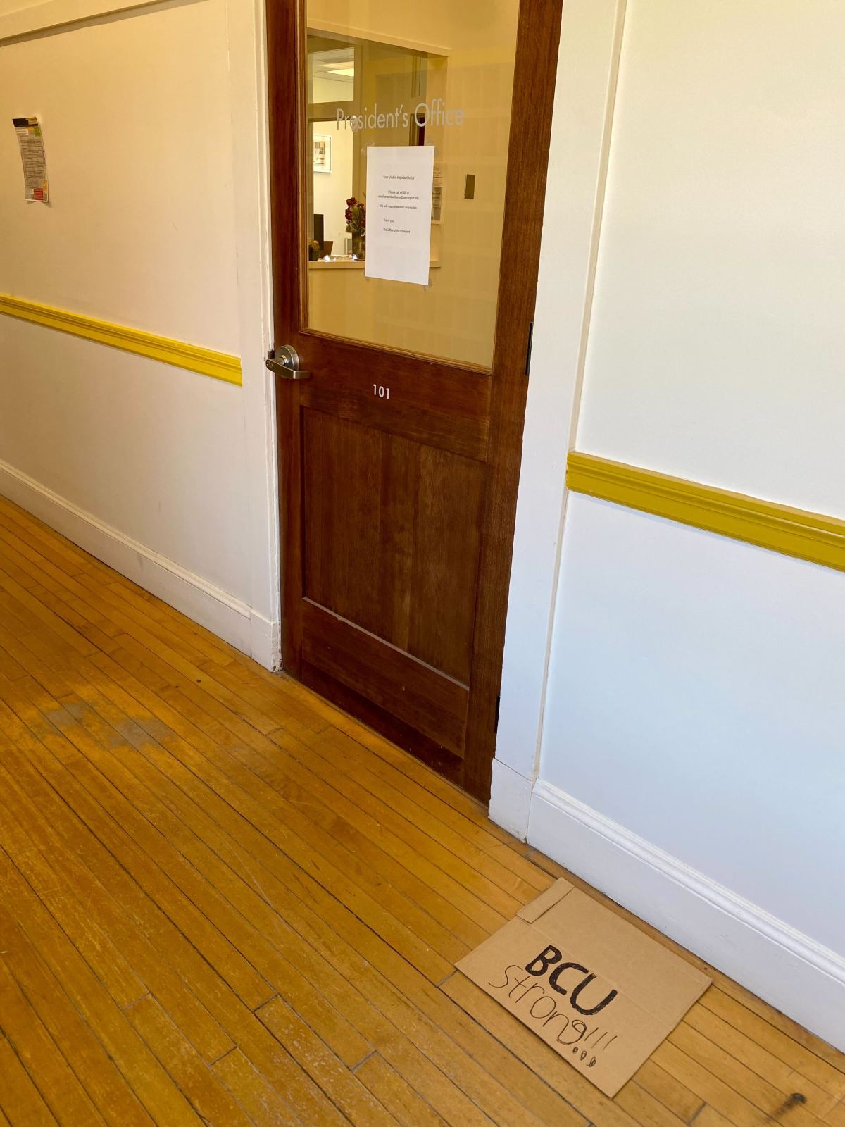 A hallway with a door and a yellow floor mat.