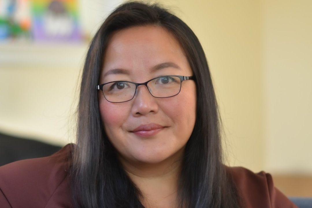 a woman wearing glasses sitting in a chair.