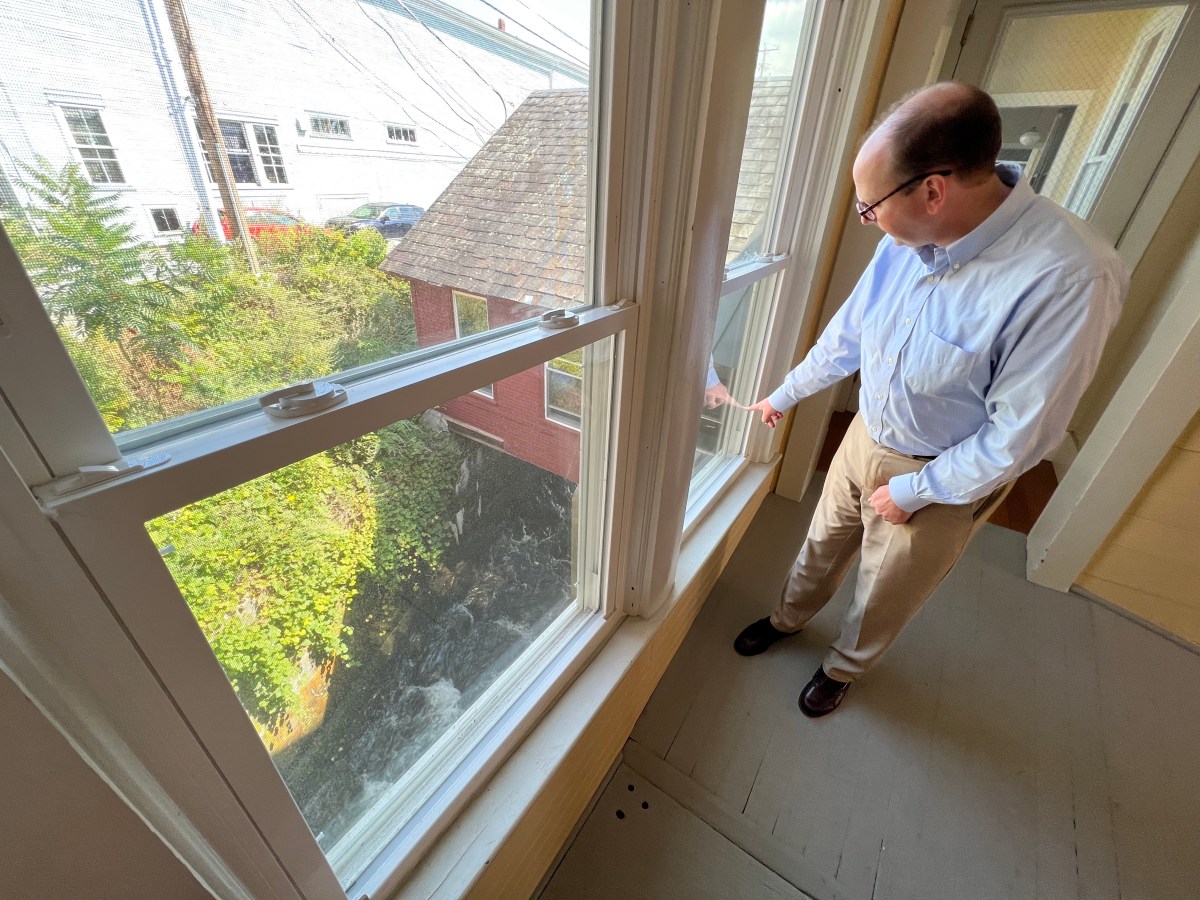 A man looking out a window in a house.