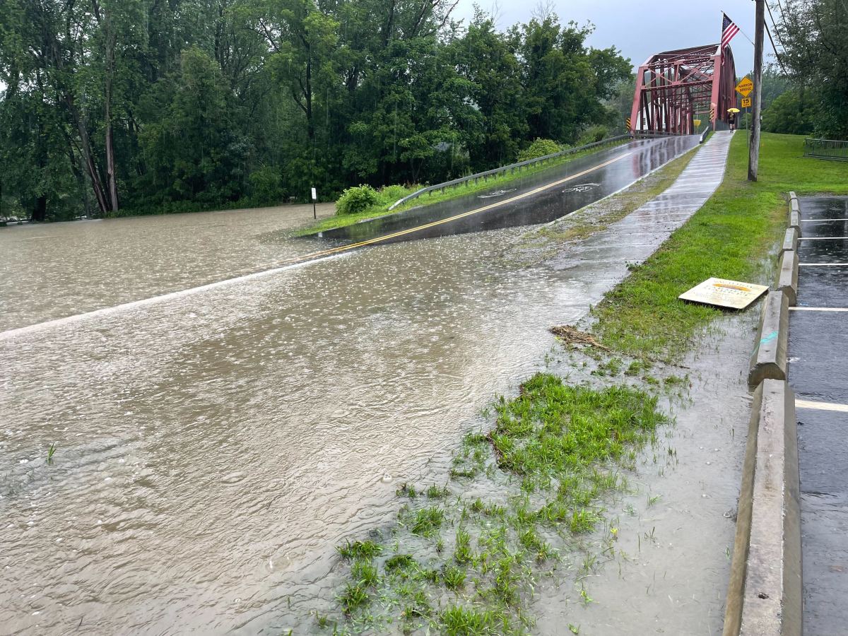 a flooded road with a bridge in the background.