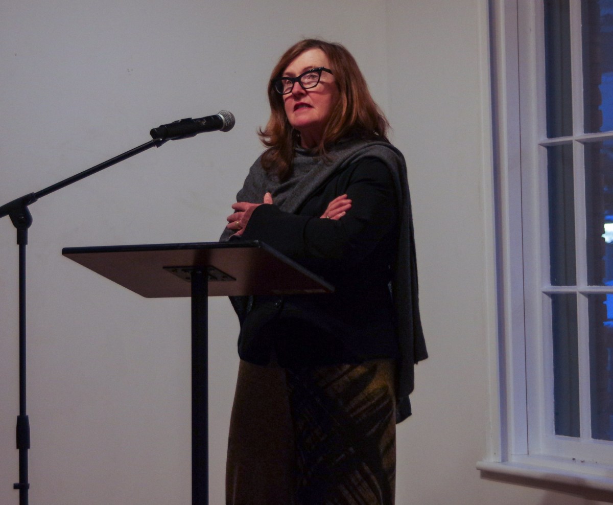 A woman in black clothing stands at a microphone