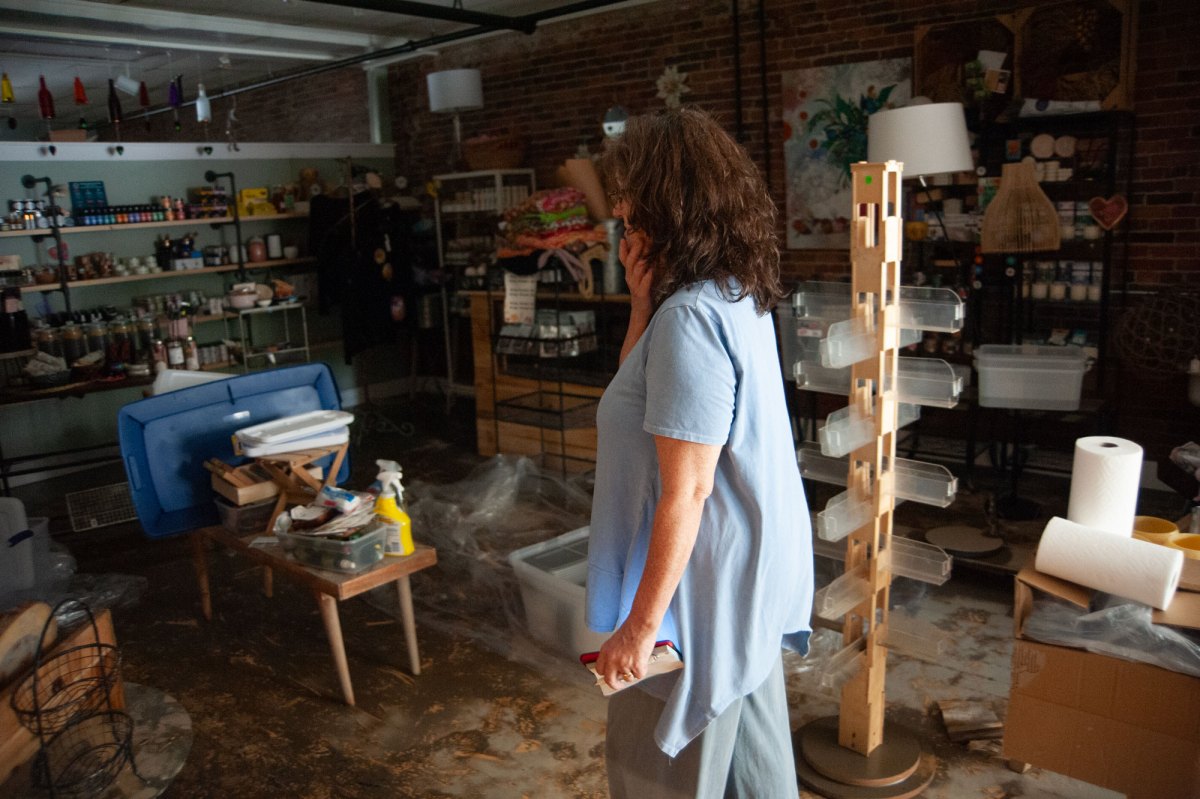 A woman in a blue shirt walks through a store.