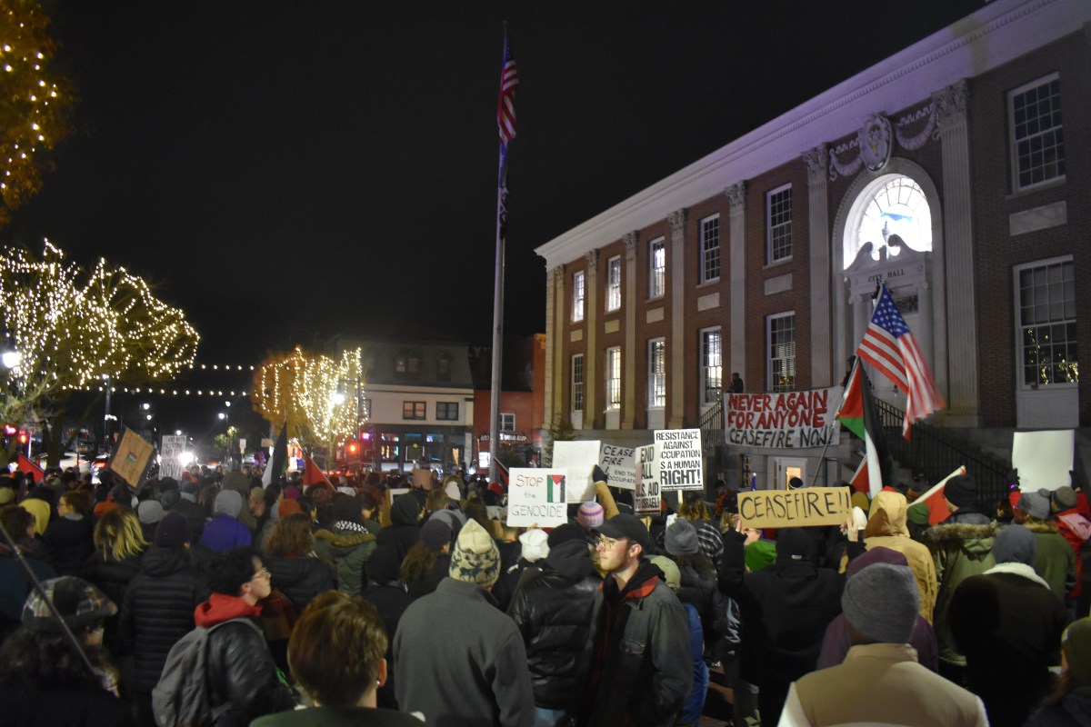 A group of people holding signs in front of a building at night.