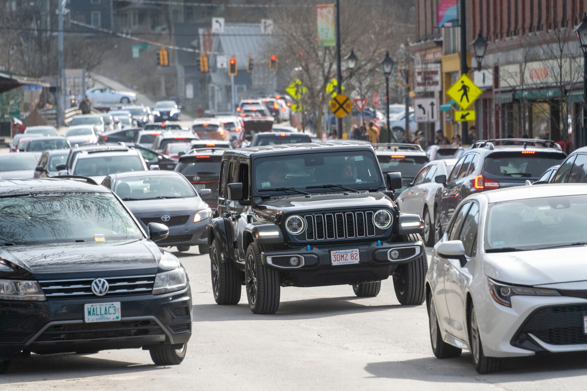 Heavy traffic on a city street with a mix of vehicles including a prominent black jeep.