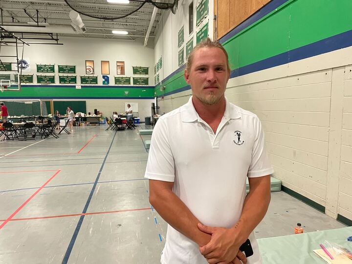 a man in a white shirt standing in a gym.