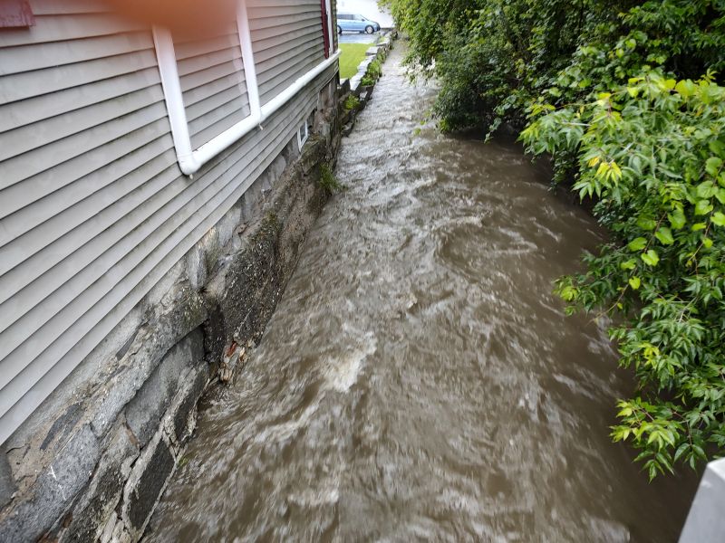 a flooded street with a house in the background.