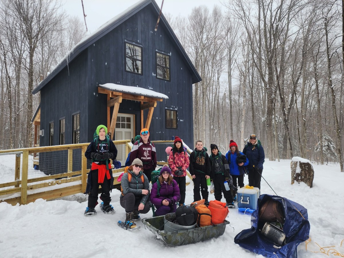 A group of people posing in front of a cabin.