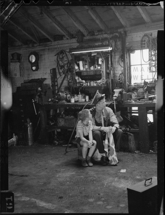 An old black and white photo of a man and a child in a garage.