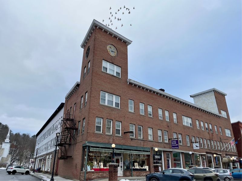 A brick building with birds flying over it.