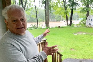 an older man standing on the porch of his home.