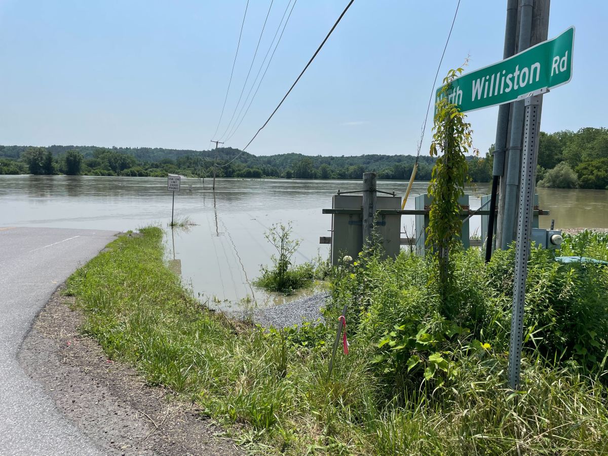 a street sign next to a flooded road.