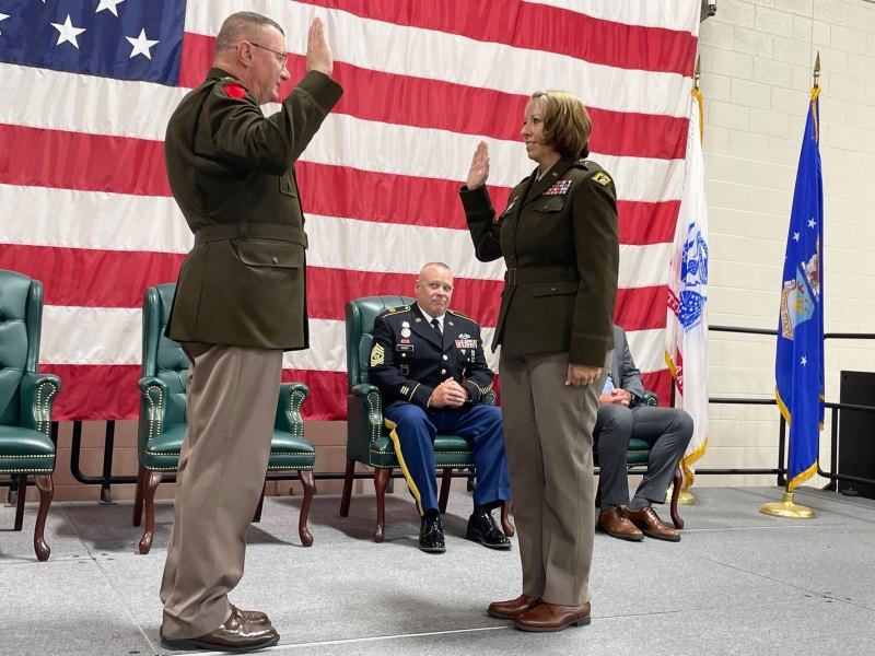 A woman in a military uniform is raising her hand