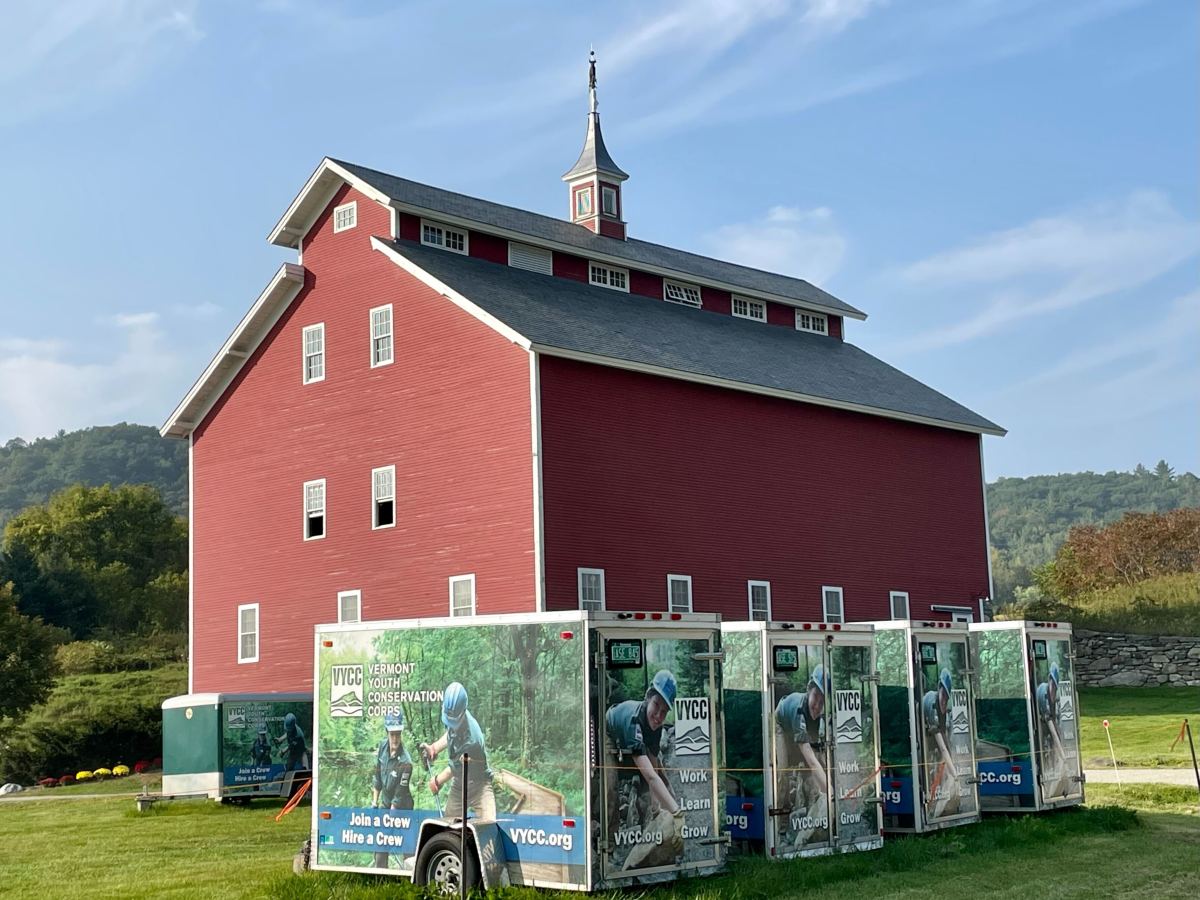 A red barn with trailers parked in front of it.