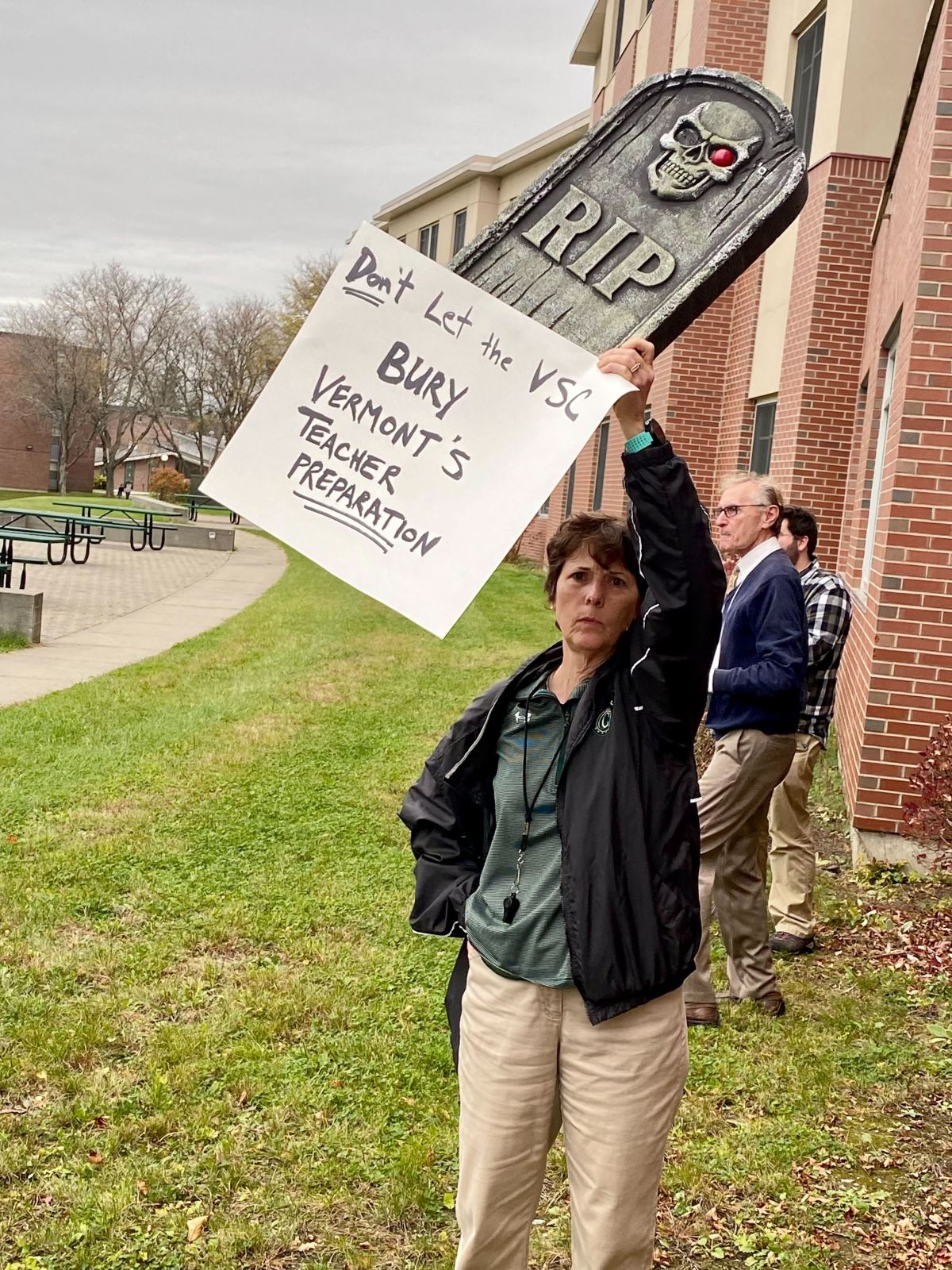A woman holds up a sign in front of a building.