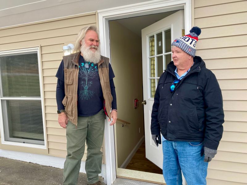 Two people talking outside a home.