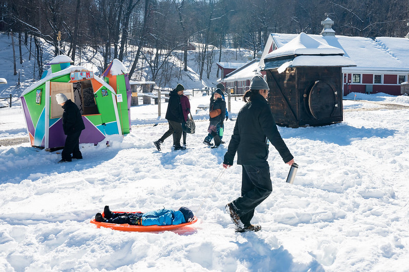 A child is laying on a sled in the snow.