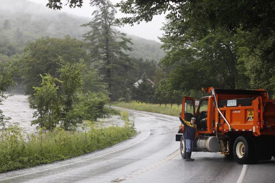 a man next to a truck on a road near a river.