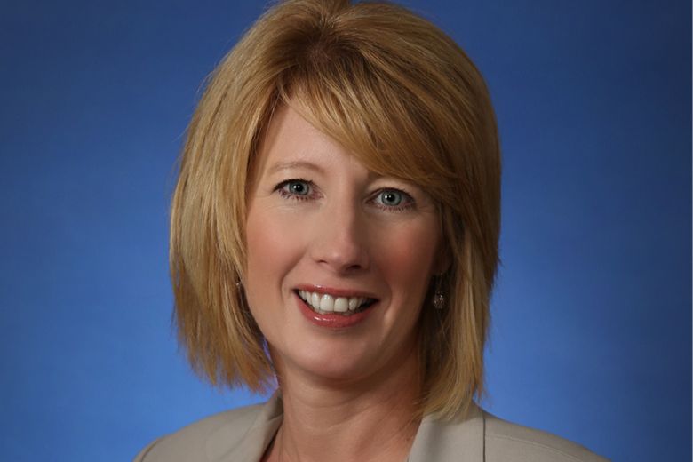a woman with blonde hair wearing a suit and smiling.