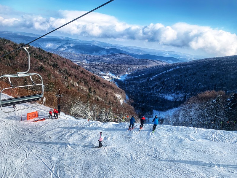 Skiers and snowboarders go down a run in the snowy mountains.