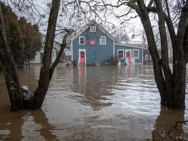 Floodwaters surround a blue building with pink doors.