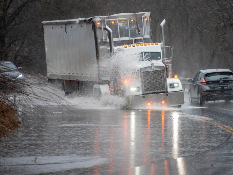 A truck drives through a partially flooded road.