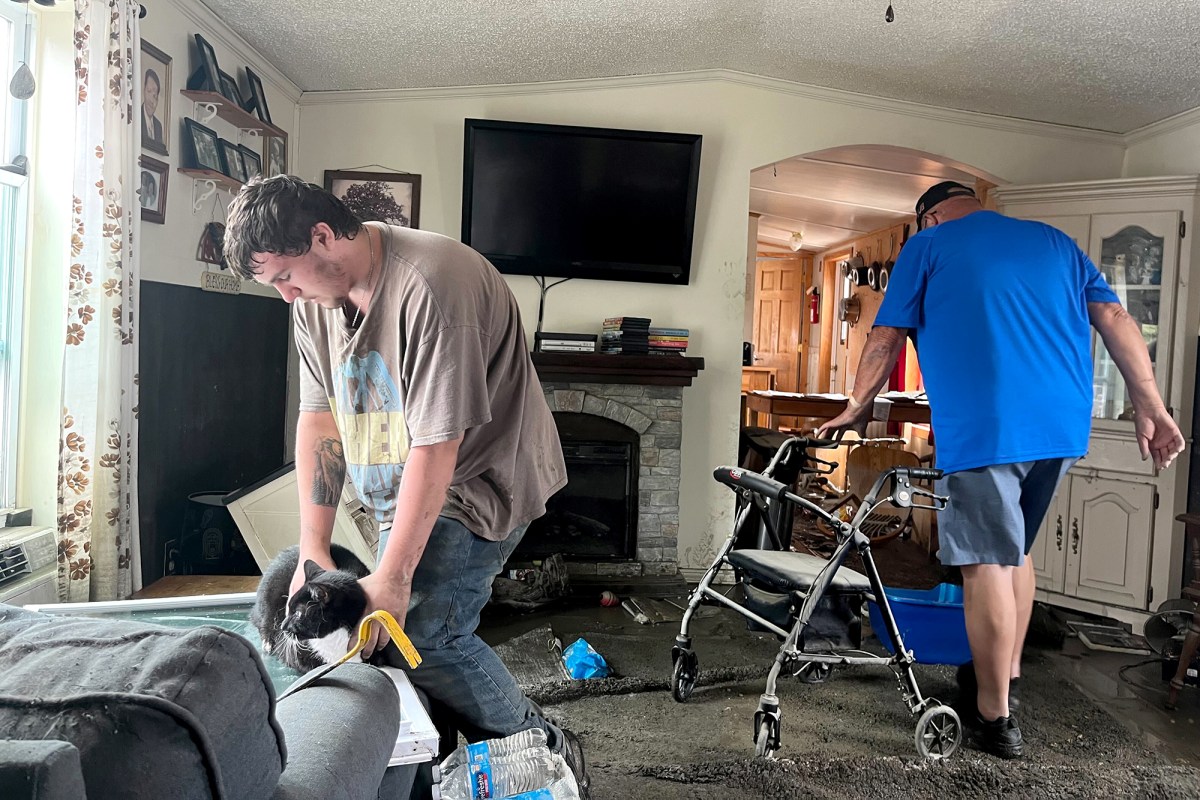 two men working in a living room with a walker.