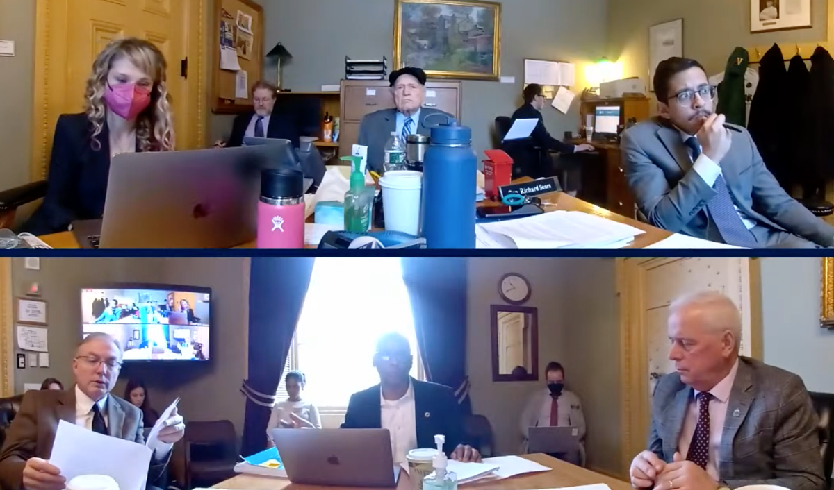 A group of people sitting at a table with laptops.