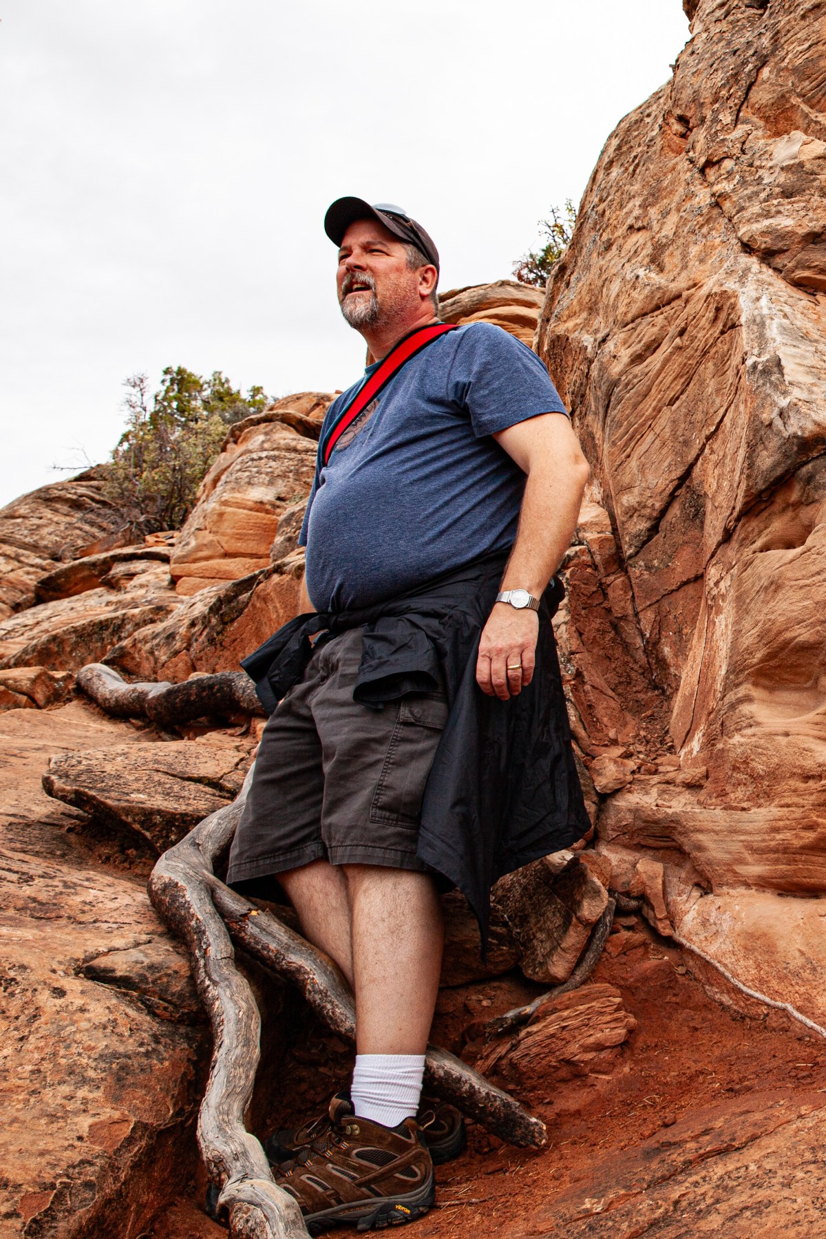 A man wearing a blue shirt standing on a rock.