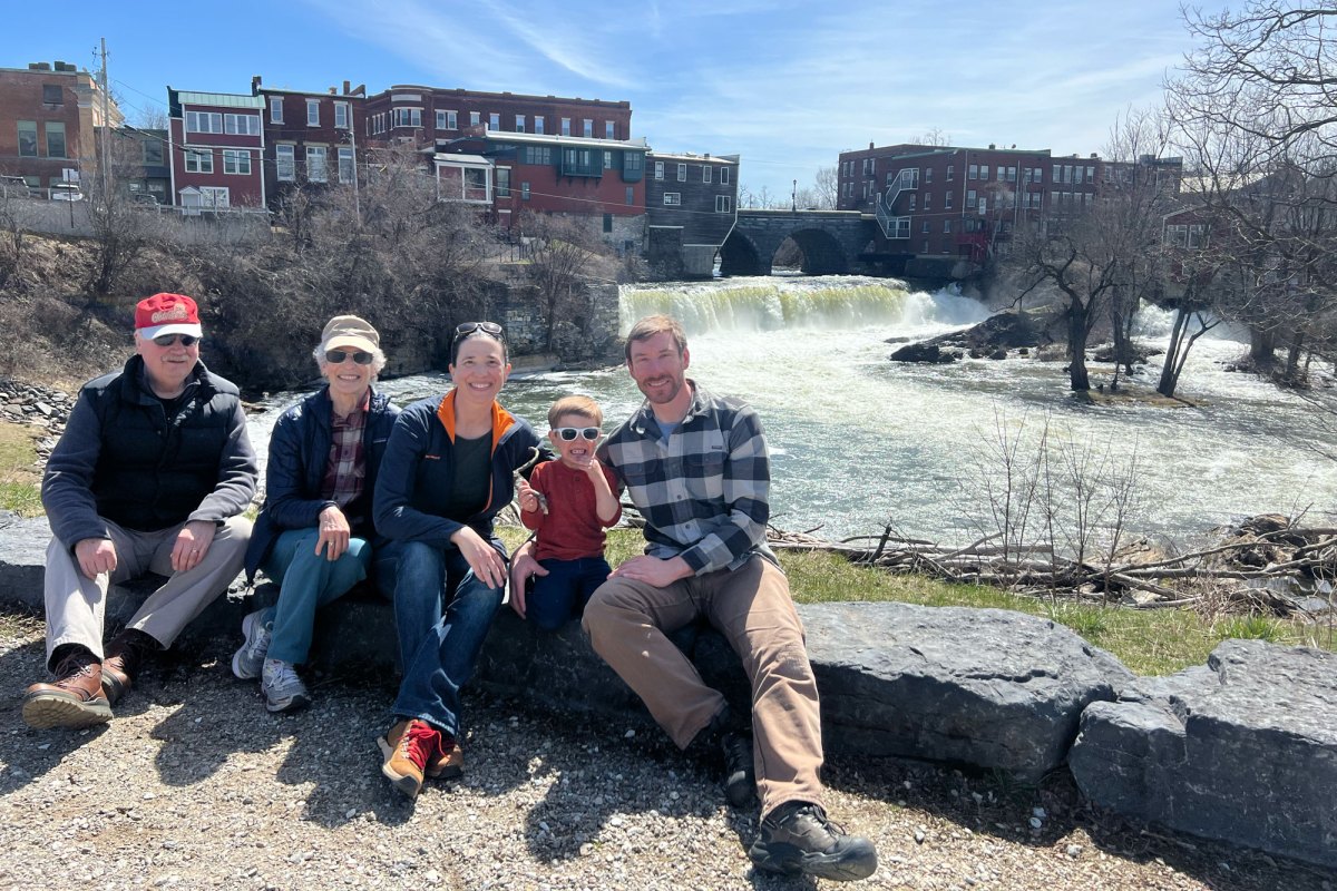 A group of people pose in front of buildings and a waterfall.