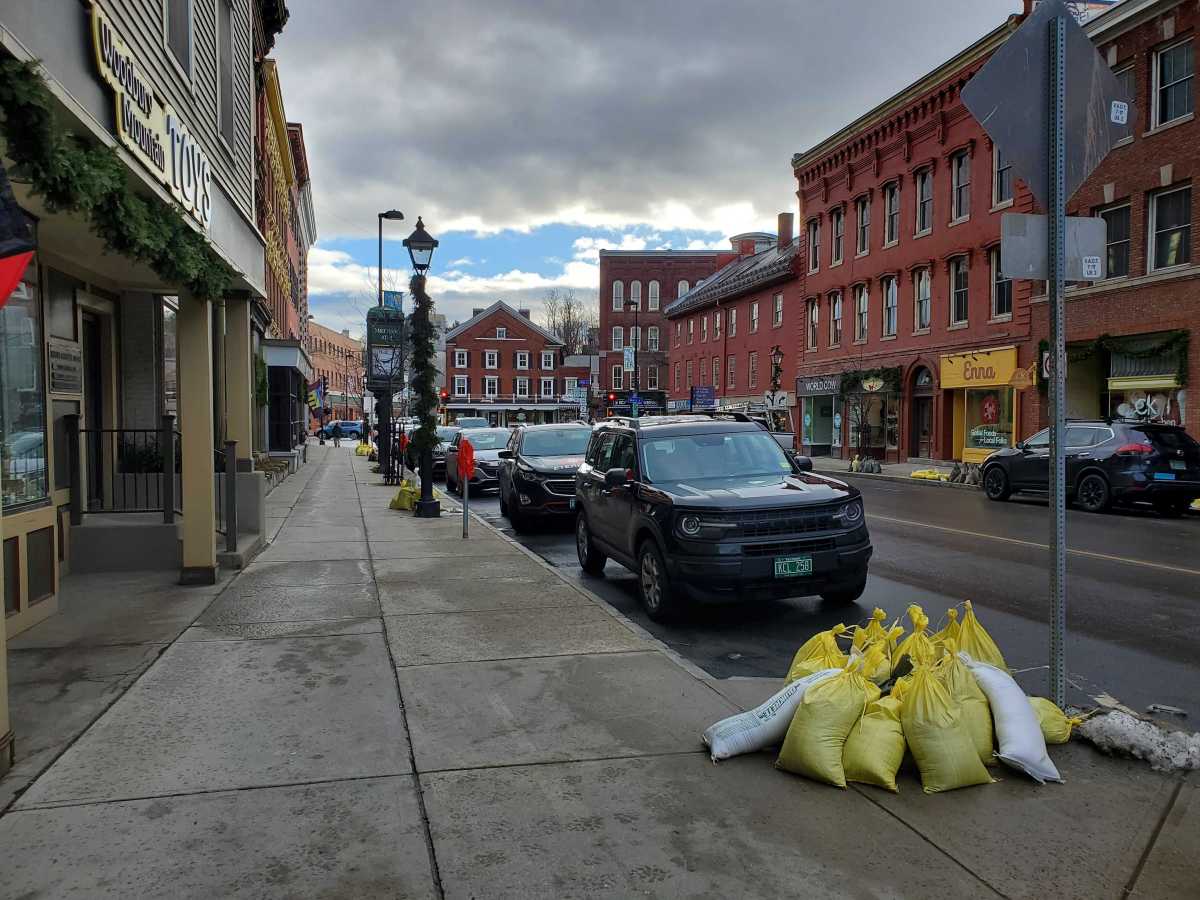 Sandbags are parked on a sidewalk in a city.