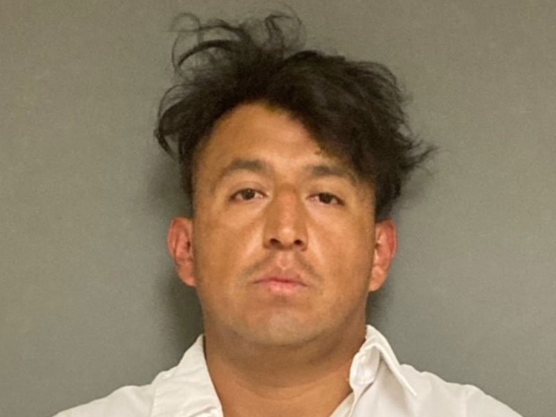 a man in a white shirt is posing for a mugshot.