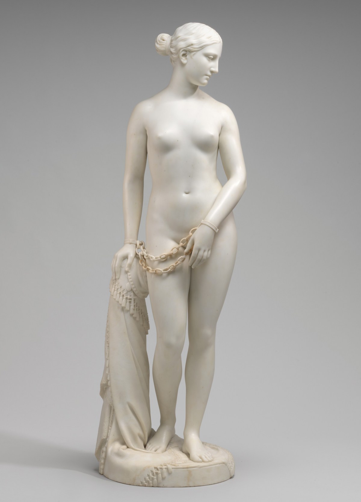 A white marble statue of a nude woman holding a scarf.