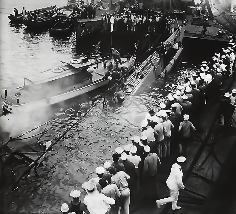A group of people standing near a submarine with smoke coming out of it.