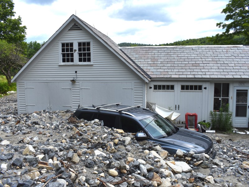 a SUV covered in rocks parked in front of a house.