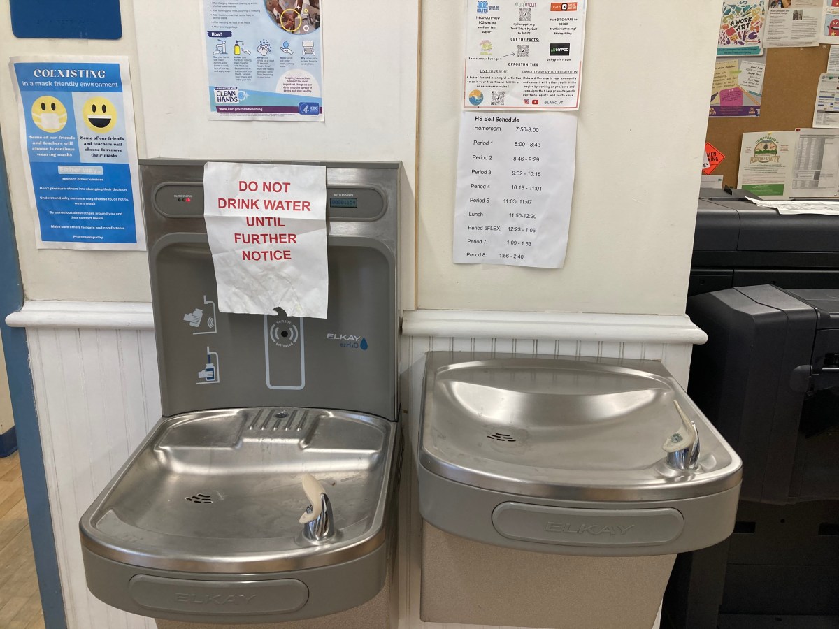 Two water fountains in a room with a sign.