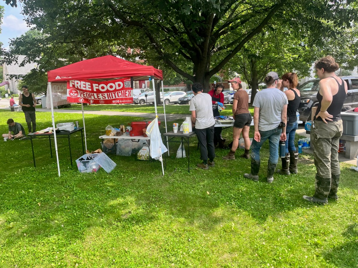a group of people standing under a tent in a park.
