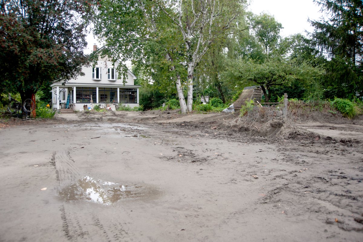 A muddy road in front of a cream-colored house.