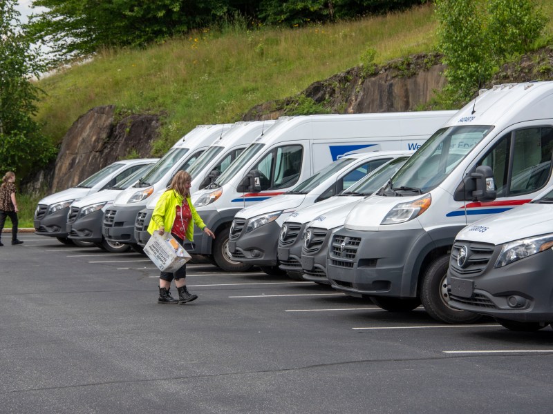 a group of white vans parked in a parking lot.