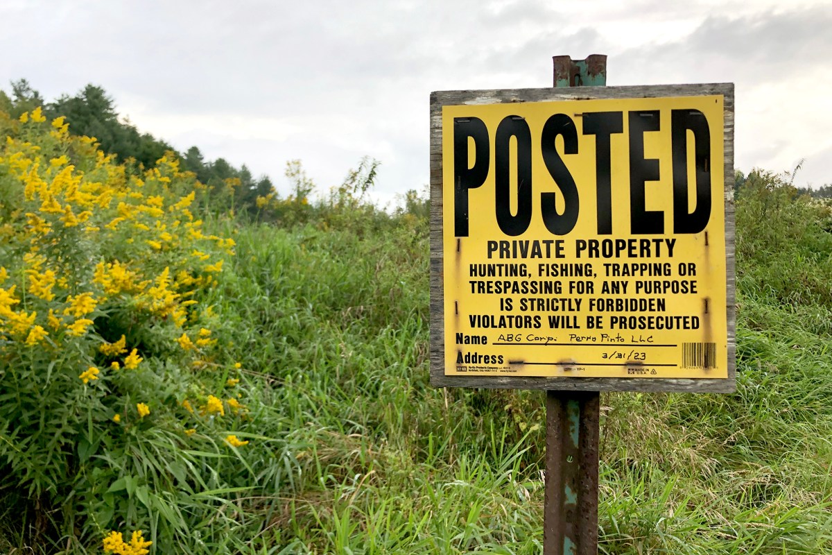 A yellow "posted" sign in a field.