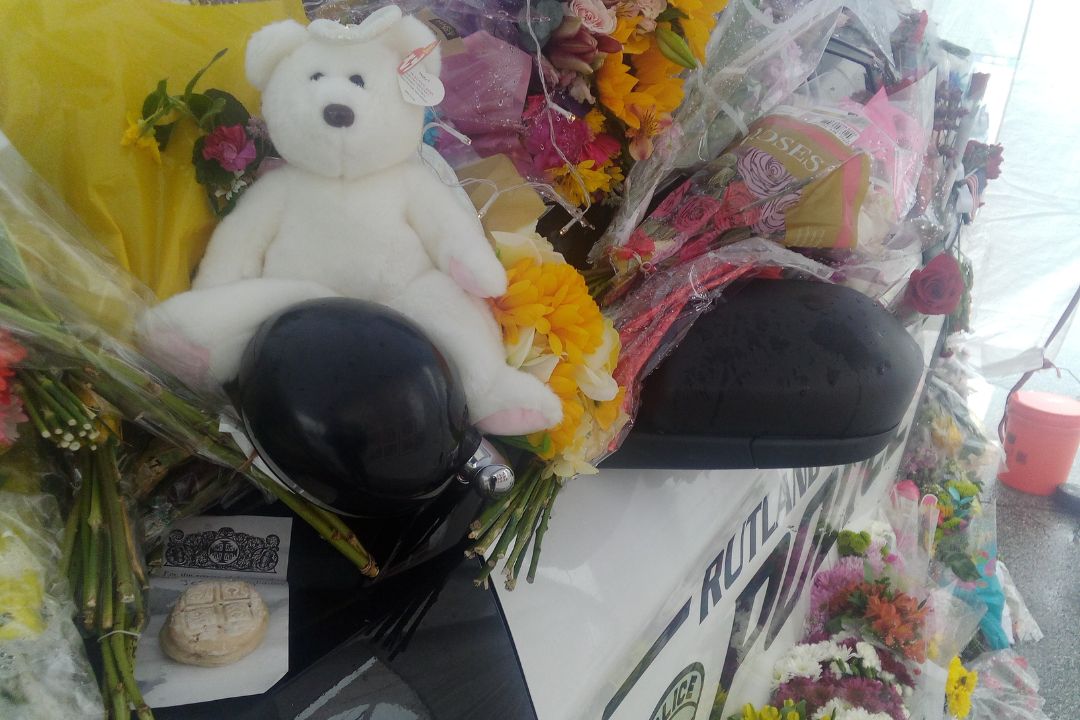 a police car with flowers and a teddy bear.