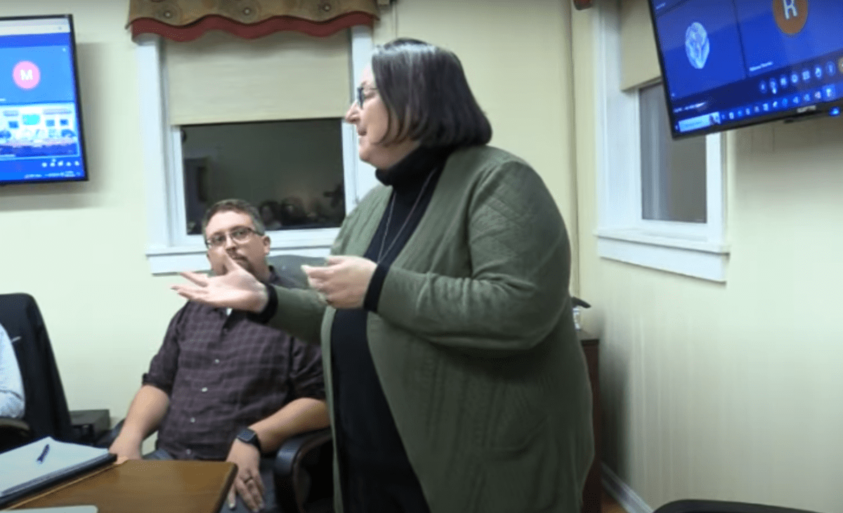 A group of people sitting at a table in front of a tv.