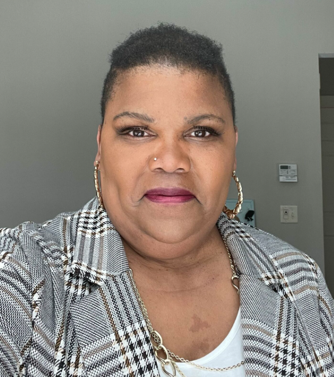 A woman in a plaid blazer taking a selfie.