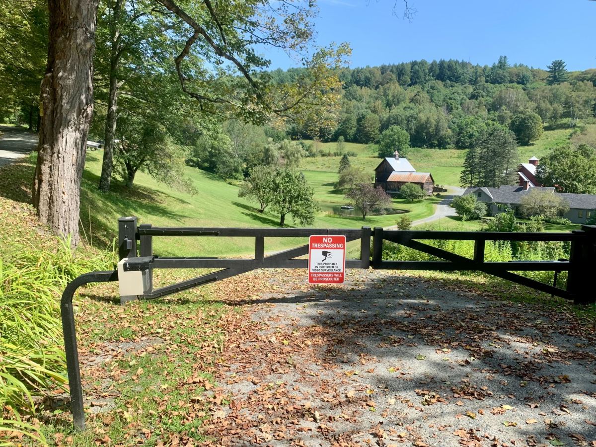 A gate with a sign on it in the middle of a field.