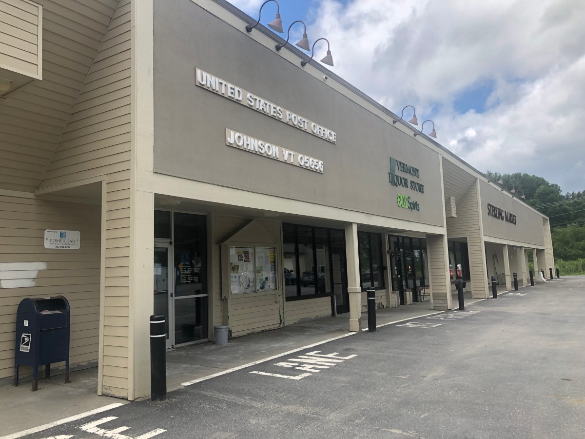 The front of a store with a parking lot and mailboxes.