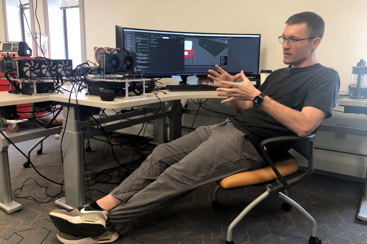 A man sitting in a chair in front of several monitors.