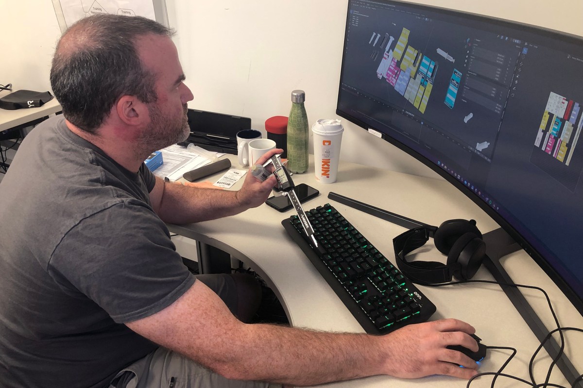 A man sitting at a desk with two monitors in front of him.