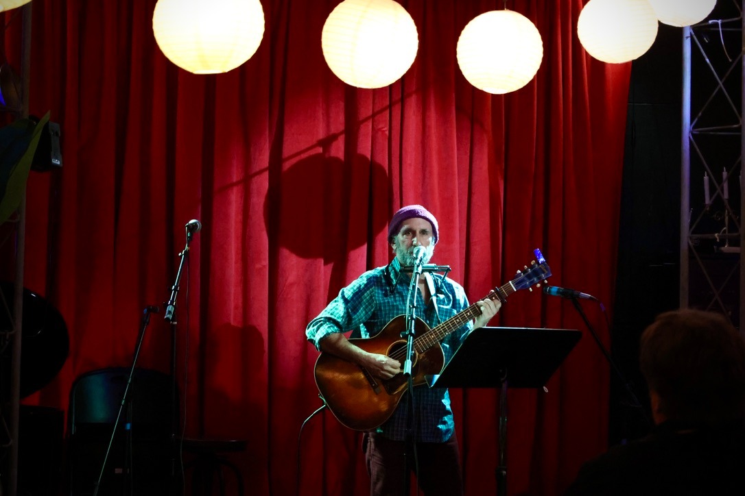 A man playing an acoustic guitar on stage.