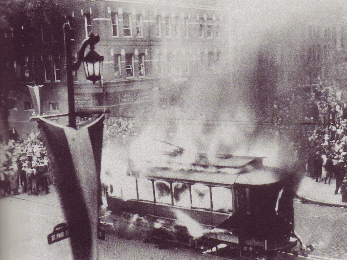 A trolley on fire in a city.