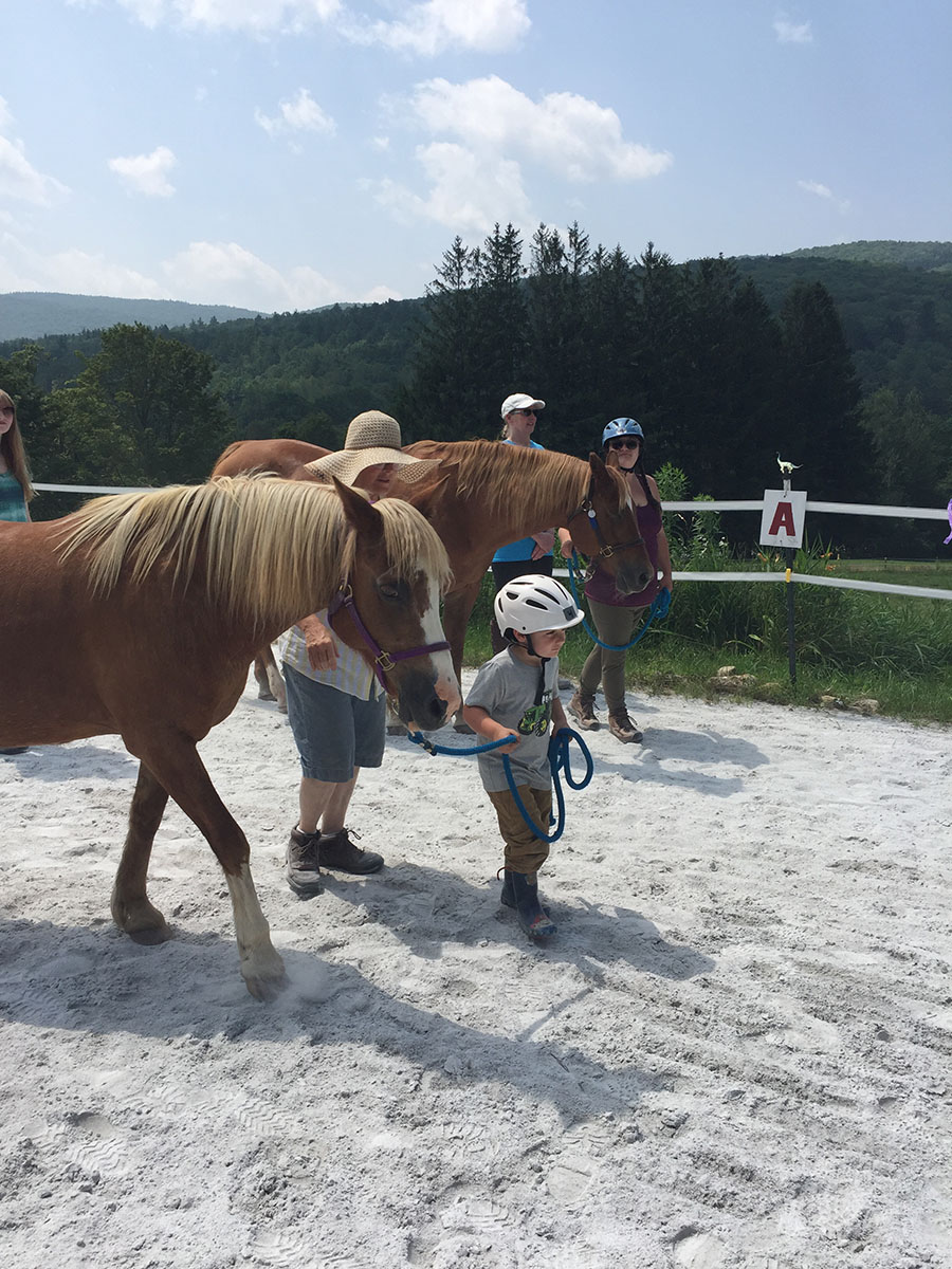 A group of people walking horses in a field.